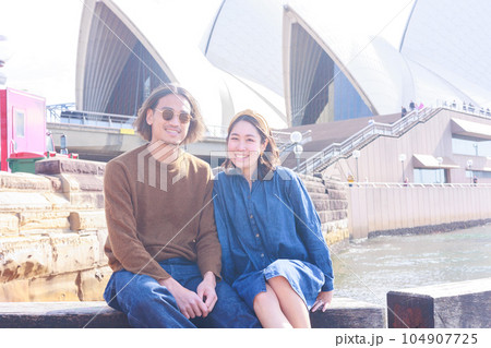 シドニーのオペラハウスの前で座る笑顔の日本人カップル 104907725