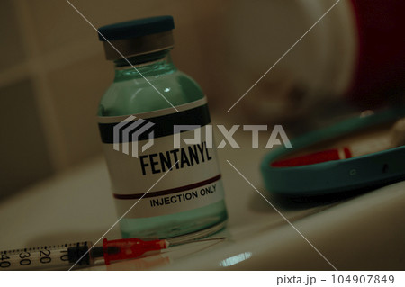 vial of fentanyl and syringe in a sordid bathroom 104907849