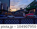 夕日を背にして都会を走る電車 104907950