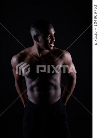Portrait of an athletic african american man topless smiling, yellow, red and black background Portrait of an athletic african american man topless smiling, yellow, red and black background 104909763