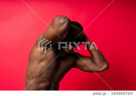 Portrait of an athletic african american man topless smiling, yellow, red and black background Portrait of an athletic african american man topless smiling, yellow, red and black background 104909784