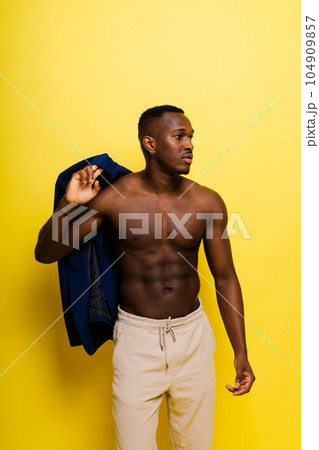 Portrait of an athletic african american man topless smiling, yellow, red and black background 104909857