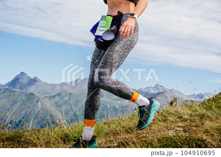 female athlete running from mountainside in leggings, mountain marathon race female athlete running from mountainside in leggings, mountain marathon race 104910695