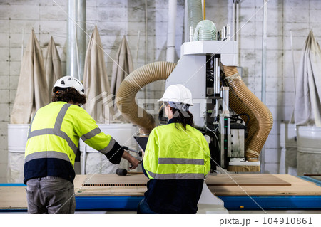 team worker work control operate wood milling machine in wood furniture workshop. technician staff teamwork working with modern industry machine 104910861
