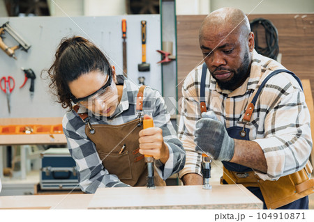 strong woman worker. builder team work. joiner in wood workshop. lady carpenter staff helping man working making furniture. hard work fix wooden board 104910871