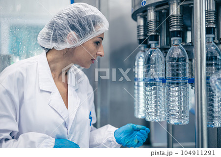 worker in drinking water factory. women workers caucasian labor in beverage clean production conveyor belt mineral water manufactory. worker in drinking water factory. women workers caucasian labor in beverage clean production conveyor belt mineral water manufactory. 104911291
