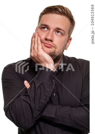 Studio portrait of gloomy european man showing boredom while leaning head on hand and standing over white background. 104913369
