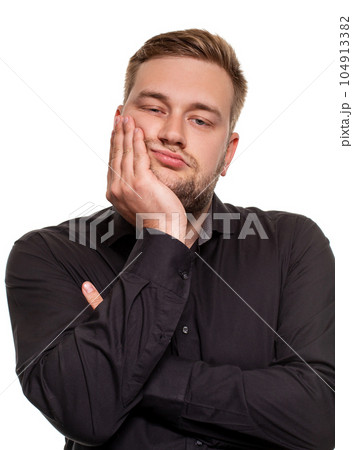 Studio portrait of gloomy european man showing boredom while leaning head on hand and standing over white background. 104913382