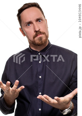 Portrait of a handsome, unshaven man, dressed in a dark blue shirt, standing against a white background. Self confident man. Portrait of a handsome, unshaven man, dressed in a dark blue shirt, standing against a white background. Self confident man. 104913446