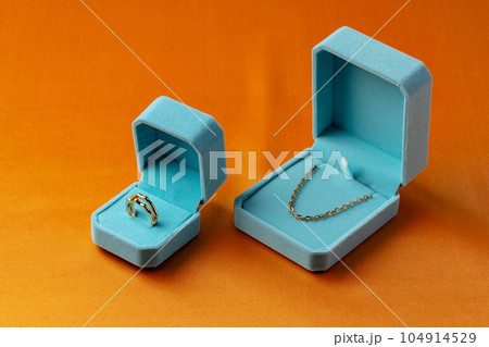 Blue boxes with golden jewelry on orange background Blue boxes with golden jewelry on orange background 104914529