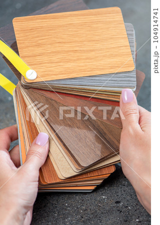 Samples of laminate in the hands of the designer. Selection of samples of laminate flooring. Samples of the floor with imitation wood of different species in the hands, close-up. 104914741