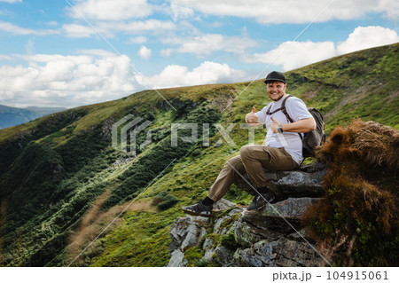 Man on top of a mountain sitting on a rock Man on top of a mountain sitting on a rock 104915061