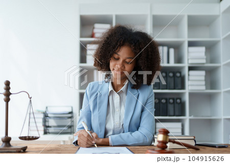 Young African American lawyer studying a case for a client and signing a legal contract to fight her opponent in court. Legal and lawyer concepts Young African American lawyer studying a case for a client and signing a legal contract to fight her opponent in court. Legal and lawyer concepts 104915626