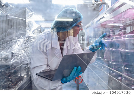 Bottling factory worker inspecting quality of water bottles before shipment. Reverse osmosis system used in plant. water purity and maintaining quality control in bottling process. High quality photo 104917330