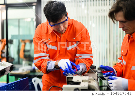 Engineers working and solving problems on machine at industrial plant 104917343