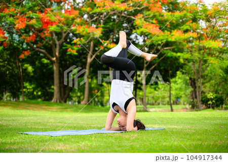 Healthy young woman enjoying and relaxing yoga outdoor in green park 104917344