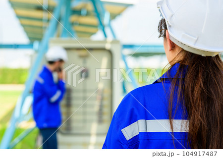Workers installing solar panels, Engineer team at solar panel farm 104917487