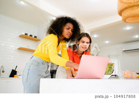 Couple of friends using laptop together at home, Women relaxing at home, Couple of female lovers spending time together, People with good relationship 104917808