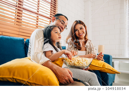 Happy family watching movie together at living room 104918034