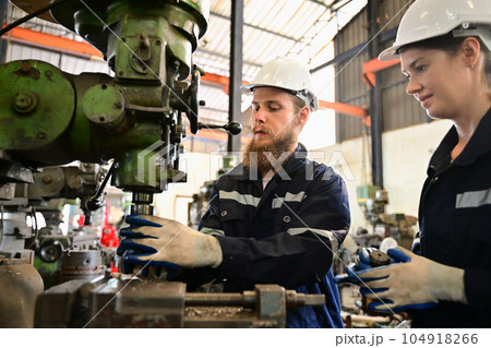 Mechanical engineers repairing engine machine at factory Mechanical engineers repairing engine machine at factory 104918266