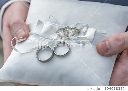Two wedding rings on a ceremonial cushion pillow beautifull decorated 104918332