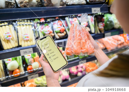 Young adult woman using phone in grocery store 104918668