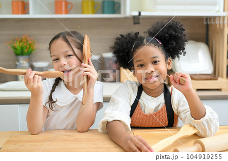 Happy children girls playing with flour and laugh in kitchen Happy children girls playing with flour and laugh in kitchen 104919255