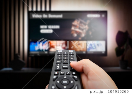 Man watching TV with remote control in hand. 104919269