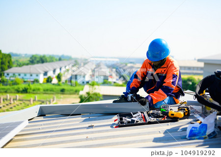 Male technician worker installing solar panels on rooftop of industrial plant Male technician worker installing solar panels on rooftop of industrial plant 104919292