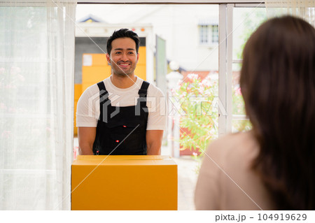 Young woman accepting and holding delivery parcel boxes from deliveryman at home, Delivery service at home 104919629