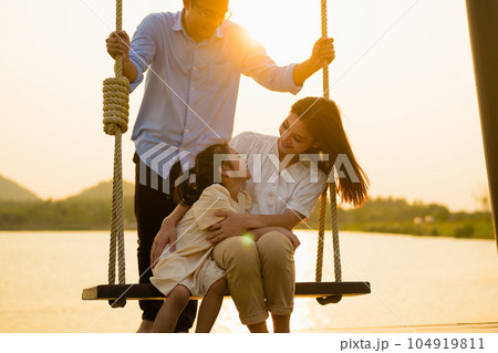 Family enjoying with outdoor activities sitting on swing with sunset 104919811