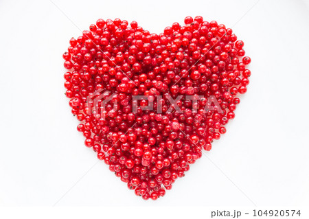 Red berries laid out in a heart shape on a white background. Big red heart from red currant. Red berries laid out in a heart shape on a white background. Big red heart from red currant. 104920574
