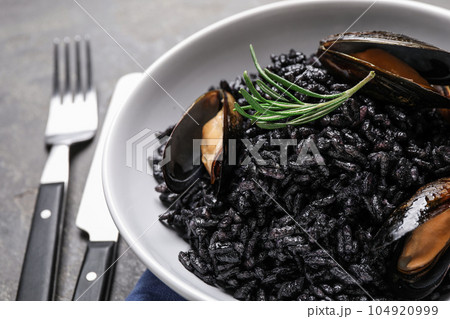 Delicious black risotto with seafood in bowl on table, closeup Delicious black risotto with seafood in bowl on table, closeup 104920999
