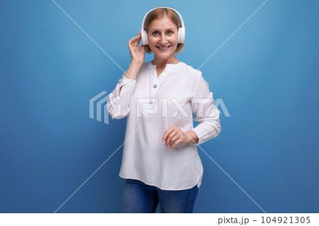 mature woman with blond hairstyle dancing to music in wireless headphones 104921305