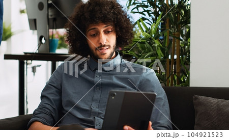 Startup consultant on videocall, using tablet to meet with executive board and present new business ideas. Young entrepreneur brings innovation in briefing videoconferece call. Handheld shot. Startup consultant on videocall, using tablet to meet with executive board and present new business ideas. Young entrepreneur brings innovation in briefing videoconferece call. Handheld shot. 104921523