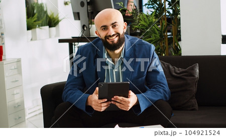 Startup analyst examining data in company office, reviewing documents before creating project. Young entrepreneur working with tablet in small business open space. Handheld shot. Startup analyst examining data in company office, reviewing documents before creating project. Young entrepreneur working with tablet in small business open space. Handheld shot. 104921524