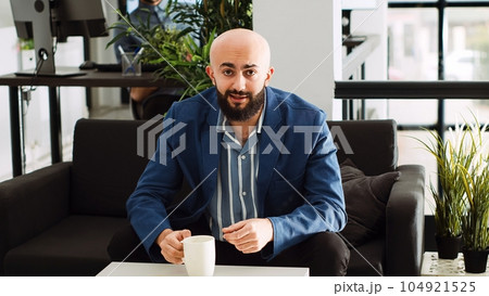 Man attends business meeting videocall to review new development strategy, using online telework call with marketing department. Startup executive manager in office coworking space. Tripod shot. 104921525