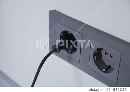 white color power cord cable plugged into wall white color power cord cable plugged into wall 104922286
