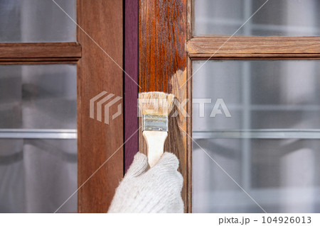 Worker use brush apply wood preserver after sandling the old surface of wooden window Worker use brush apply wood preserver after sandling the old surface of wooden window 104926013