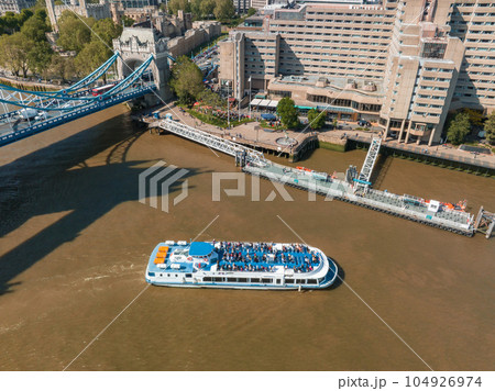Tourist boat exploring London under the Tower Bridge. Tourists in London. Holiday conception. 104926974