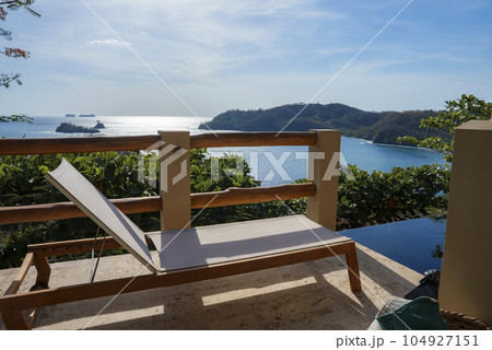 Luxury resort with deckchair by swimming pool in front of beautiful seascape during sunny day at Costa Rica 104927151