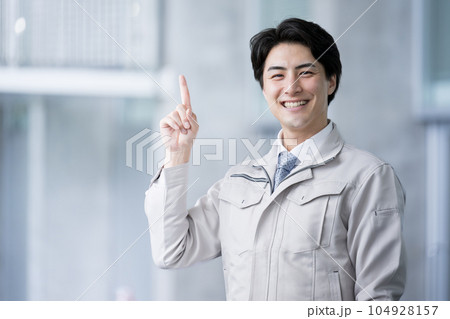 作業着で指差しポイントや紹介、案内をするハンサムな男性 104928157