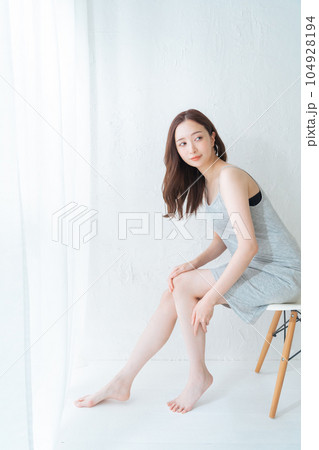 椅子に座って脚のスキンケアとマッサージをする若い女性 104928194