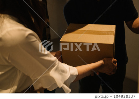 宅配業者から荷物を受け取る女性 104928337