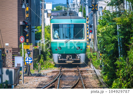 日本の鎌倉都市景観　人気のローカル線・江ノ電（後部車両）。民家の軒がせまる光景や小さな踏切… 104929787