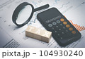 Tax word on wooden block with phone app calculator and magnifying glass. 104930240