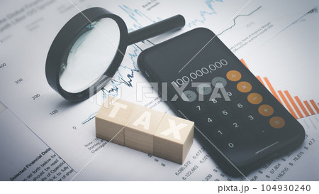 Tax word on wooden block with phone app calculator and magnifying glass. 104930240