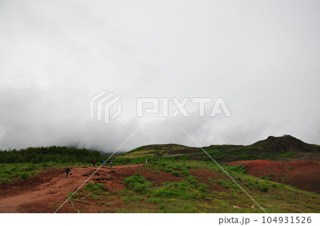Aerial view of people climbing up a foggy mountain near Kerid Crater in Iceland 104931526