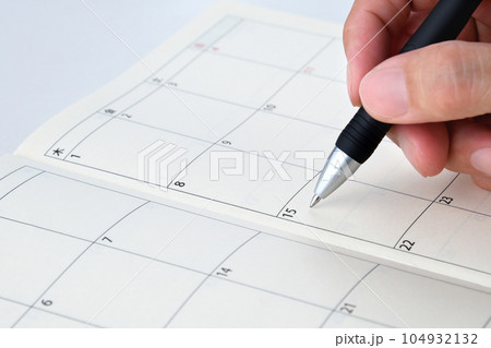 手帳に予定を書き込む人物の手元 104932132