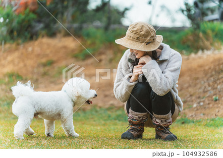 秋冬のキャンプ場で愛犬と遊ぶキャンパーのアジア人女性(ビジョンフリーゼ) 秋冬のキャンプ場で愛犬と遊ぶキャンパーのアジア人女性(ビジョンフリーゼ) 104932586